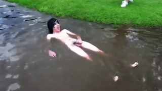 Teen boy having fun naked outdoors in front of friends